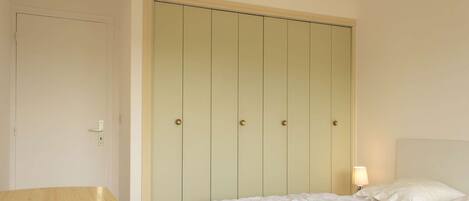 Un dormitorio con cama, mesita de noche y armario de cinco puertas.