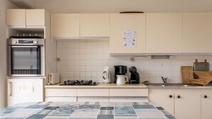 Een kleine keuken met een inbouwoven, een koffiezetapparaat en een waterkoker op het aanrecht.