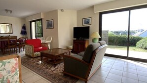 A living room with a sofa, armchair, TV, and dining area. - House with terrace in Erquy | 6 guests | Ref 603 (ERQUY)