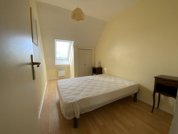 A bedroom with a single bed, a small bedside table, a window, and a door. - House with terrace in Erquy | 6 guests | Ref 603 (ERQUY)