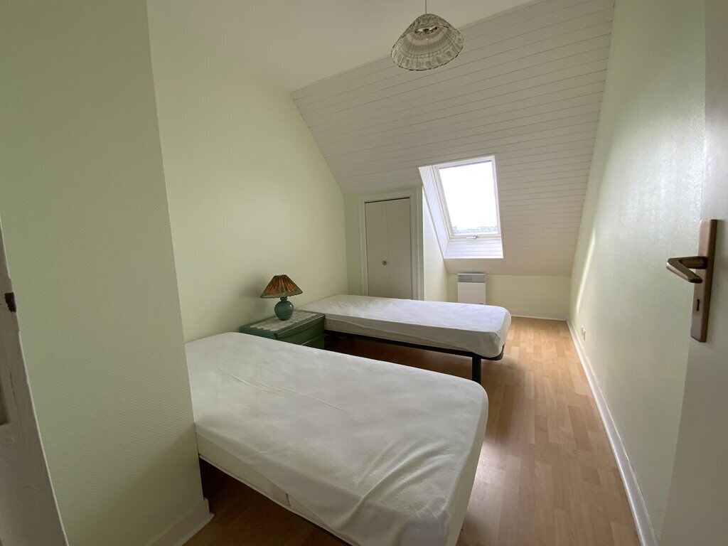 A small, single-room with two beds, a skylight, and a wooden floor.