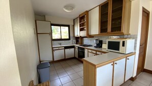 A kitchen with wooden cabinets, a microwave, a stove, and a window. - House with terrace in Erquy | 6 guests | Ref 603 (ERQUY)