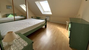 A bedroom with a sloped ceiling, a skylight, a bed, a dresser, and a bedside table with a lamp. - House with terrace in Erquy | 6 guests | Ref 603 (ERQUY)