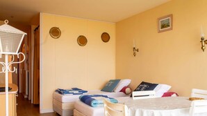 Una habitación acogedora con una cama, una mesita pequeña y una silla. Hay tres espejos redondos en la pared, una lámpara de pared y un marco de fotos.