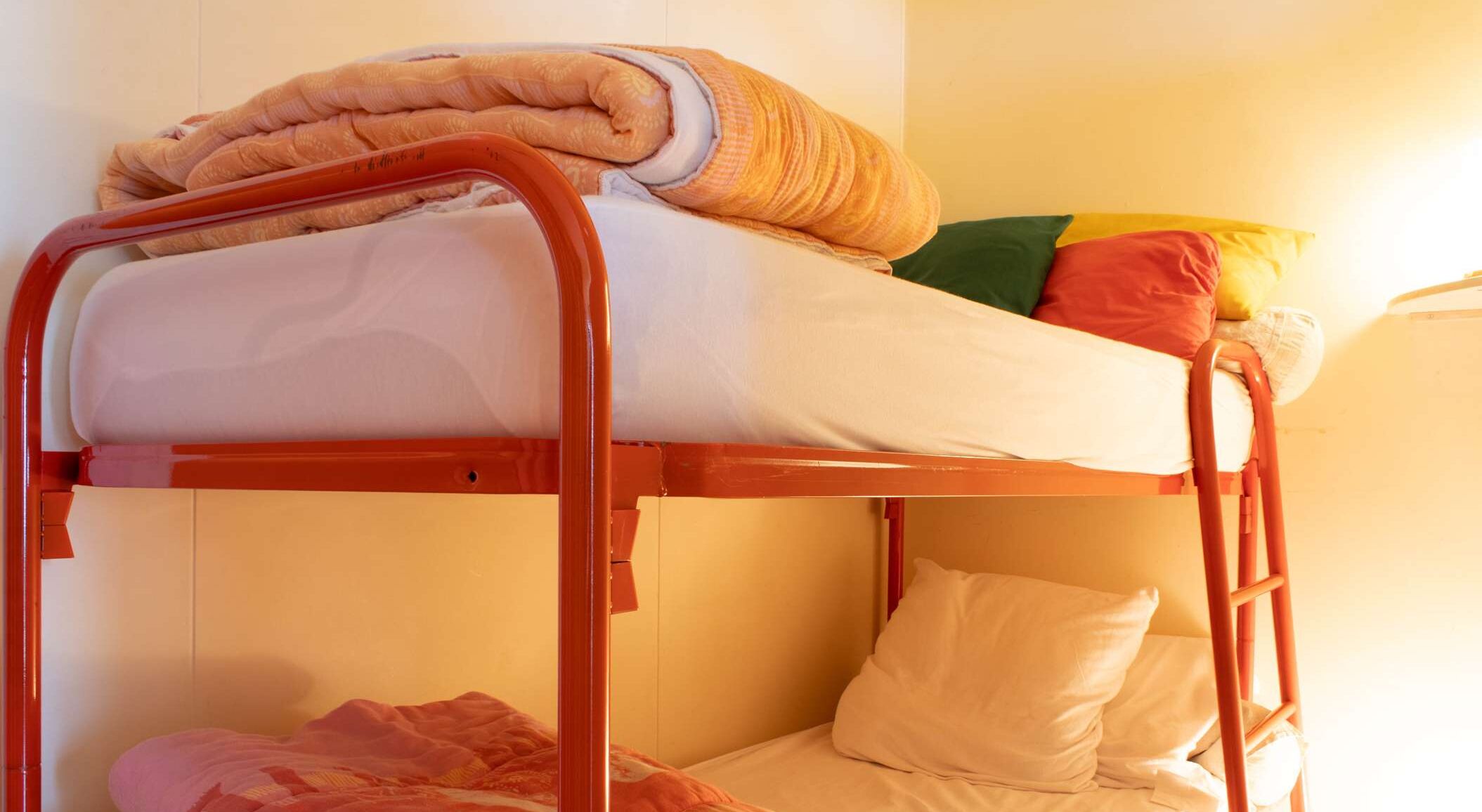 A bunk bed with a mattress, pillows, and a blanket.