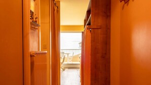 Un pasillo estrecho con puertas de madera que dan a un balcón con mobiliario exterior.