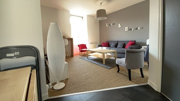 A modern living room with a grey sofa, red cushions, a white coffee table, and a standing fan. - Apartment near beach in Erquy | 5 guests | Ref 653 (ERQUY)