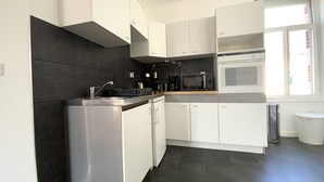A modern kitchen with white cabinets, a black backsplash, and a built-in oven. - Apartment near beach in Erquy | 5 guests | Ref 653 (ERQUY)