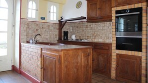 Een keuken met houten kastjes, een inbouwoven en een betegelde spatwand.