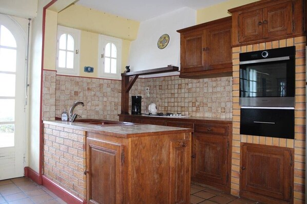 A kitchen with wooden cabinets, a built-in oven, and a tiled backsplash. - House 50 m from the beach in Erquy | Ref 702 (ERQUY)