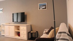 Un salon moderne avec un téléviseur à écran plat fixé à un meuble, un canapé à rayures et une petite table d’appoint.