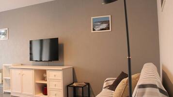 A modern living room with a flat-screen TV mounted on a cabinet, a striped sofa, and a small side table.