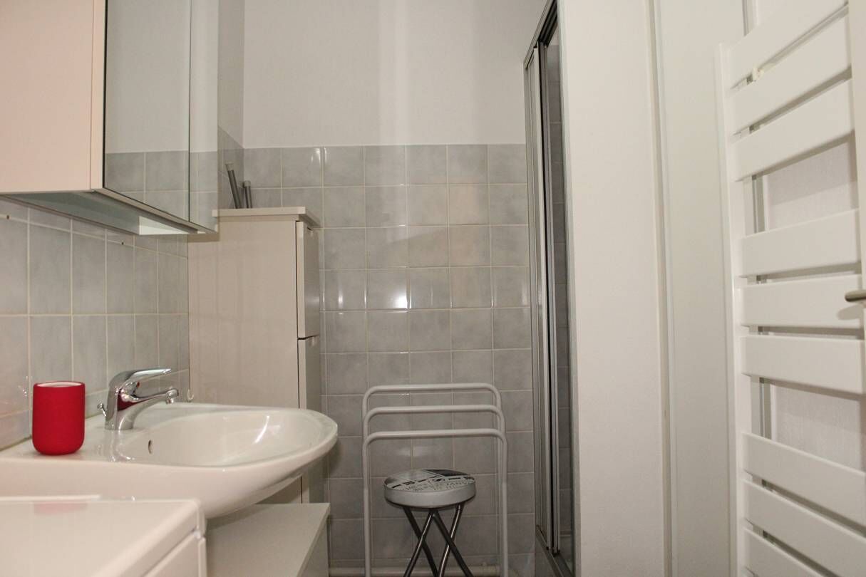 A bathroom with a white sink, a red cup, and a shower area.