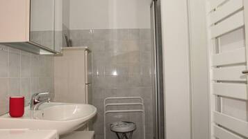 A bathroom with a white sink, a red cup, and a shower area.