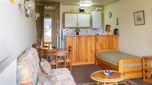 En kompakt bolig med sofa, et lille spisebord, et tekøkken og en seng.