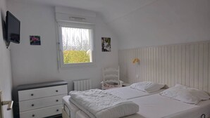 A bedroom with a bed, a dresser, a radiator, and a window with a view of greenery. - House with garden in Erquy | 6 guests | Ref 602 (ERQUY)