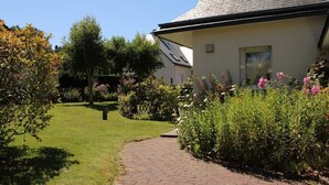 A pathway leading to a building with a sloped roof, surrounded by well-maintained gardens and various plants. - House with garden in Erquy | 6 guests | Ref 602 (ERQUY)