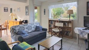 A living room with a sofa, a coffee table, a bookshelf, a TV, and a dining area with a table and chairs. - House with garden in Erquy | 6 guests | Ref 602 (ERQUY)