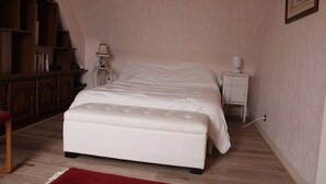 A bedroom with a bed, a nightstand, a lamp, a bookshelf, and a red rug.