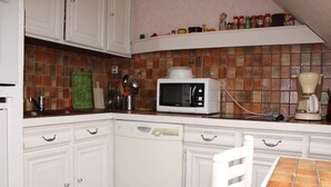 A kitchen with white cabinets, a microwave, a coffee maker, and a tiled backsplash.
