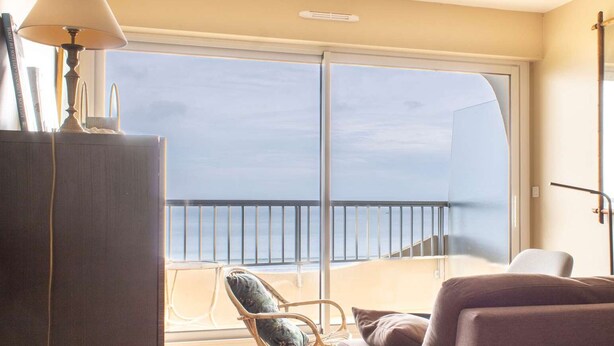 A room with a large window, a sofa, a chair, and a lamp. - Sea-view apartment in Erquy 50 m from the beach | 4 guests | Ref 411 (ERQUY)