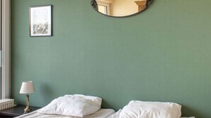 A bedroom with a bed, two pillows, a bedside lamp, a framed picture, and a round mirror on the wall. - Sea-view apartment in Erquy 50 m from the beach | 4 guests | Ref 411 (ERQUY)