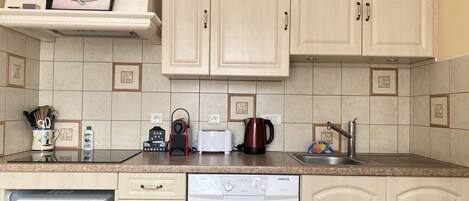 A kitchen with beige cabinets, a microwave, a dishwasher, a toaster, and a coffee maker.