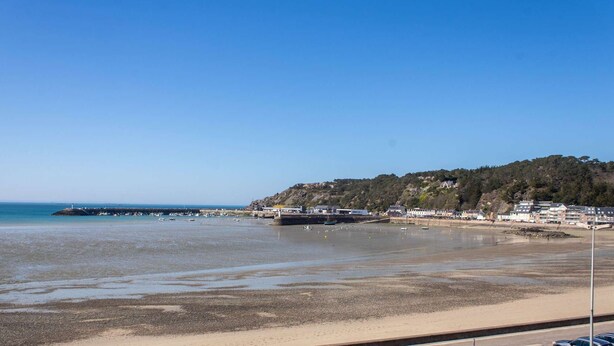 A coastal area with a sandy beach, a rocky hill with buildings, and a lighthouse in the distance. - Sea-view apartment in Erquy | 4 guests | Ref 514 (Erquy)