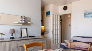 A cozy room with a wooden desk, a chair, a bed with striped bedding, and a door leading to another room. - Sea-view apartment in Erquy | 4 guests | Ref 514 (Erquy)
