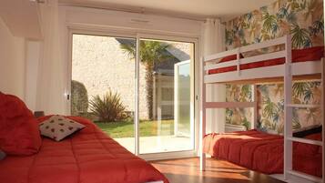 Ein Schlafzimmer mit einem Bett, einem Etagenbett und einer Glasbalkonschiebetür.