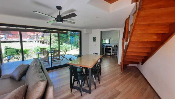 Ein modernes Wohnzimmer mit einem Holzesstisch, einer Couch und einer Treppe.