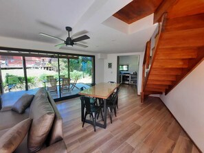 Un salon moderne avec une table à manger en bois, un canapé et un escalier.
