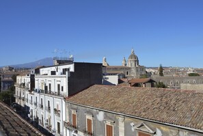 Paisatge urbà amb edificis històrics, una església destacada amb cúpules i una muntanya al fons.