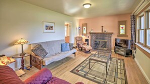 Una sala de estar con sofá, sillón, chimenea y televisor.