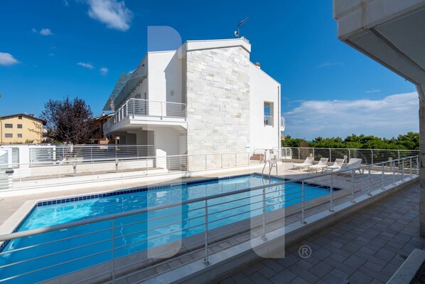 A modern building with a swimming pool and outdoor seating.