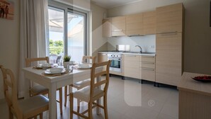 Una cocina moderna con armarios de madera clara, horno integrado y comedor con mesa dispuesta para cuatro.