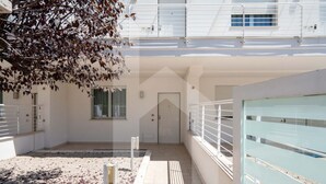 Un edificio moderno con un área exterior techada, una puerta y un banco.