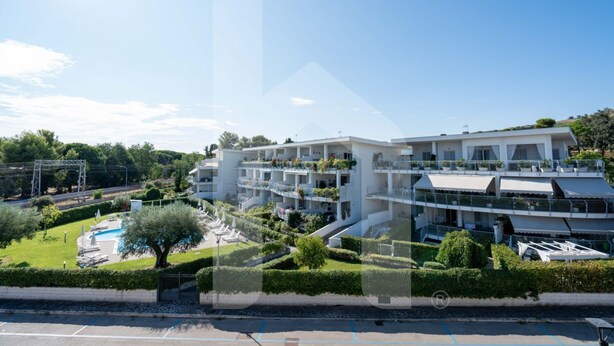 Un hôtel moderne doté de nombreux balcons, d’une piscine et de jardins bien entretenus.