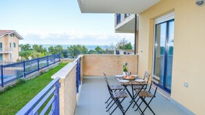A balcony with a table and chairs, overlooking a coastal area. - G.Bay D02 - Ground floor apartment with balcony, hill view (Foggetta)