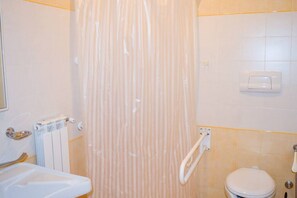 A bathroom with a shower curtain, a toilet, a sink, and a towel rack.