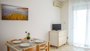 A dining area with a table set for two, a potted plant, and a painting of a landscape. - G.Bay D02 - Ground floor apartment with balcony, hill view (Foggetta)