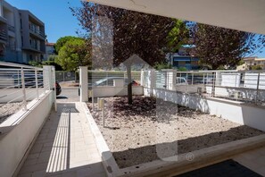 A covered outdoor area with a gravel path, metal railings, and a tree.