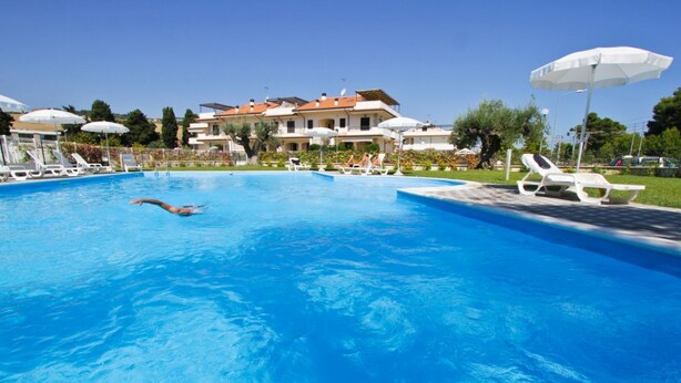 A swimming pool with lounge chairs and umbrellas, surrounded by buildings. - Mykonos B7 - Apollo - 2-room apartment with terrace and sea view (Pineto)
