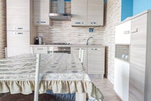 Een koelkast, een oven, een kookplaat, kookgerei, borden en bestek