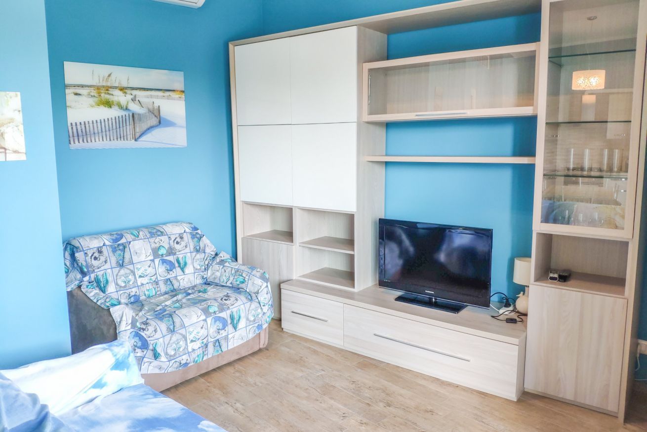 Una stanza con un letto, un divano, una TV e scaffali a muro.