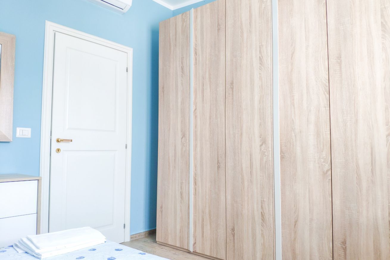 A room with a bed, a wardrobe, and a door.