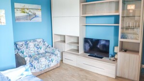 A room with a bed, a sofa, a TV, and built-in shelving. - Mykonos B7 - Apollo - 2-room apartment with terrace and sea view (Pineto)