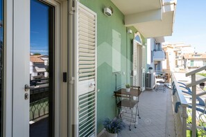 A balcony with a table and chairs, a potted plant, and a view of neighboring buildings. - D'Annunzio Residence - Galene - Apartment a stone's throw from the sea (Pineto)