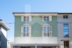 Un edificio de dos pisos con fachada verde y detalles blancos.