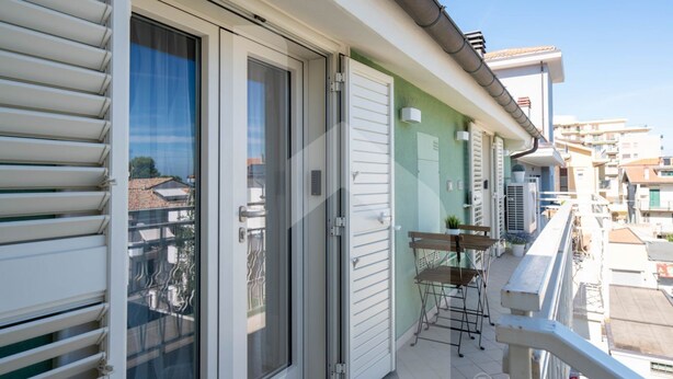 A balcony with a sliding glass door, a small table with chairs, and a potted plant. - D'Annunzio Residence - Sedna - Apartment a stone's throw from the sea (Pineto)